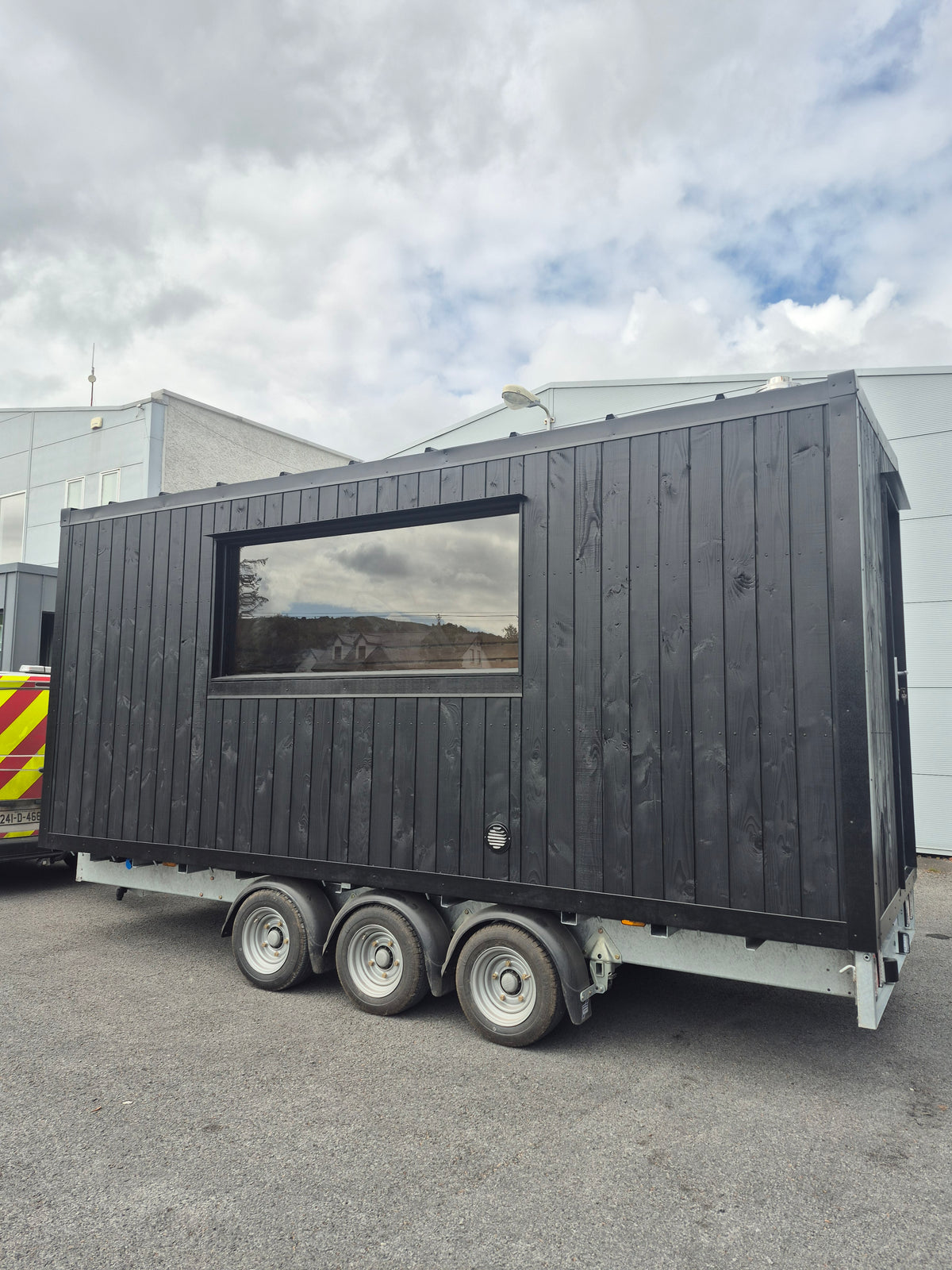 Exterior side view of the Atlantic commercial mobile sauna with panoramic window and tri-axle trailer chassis