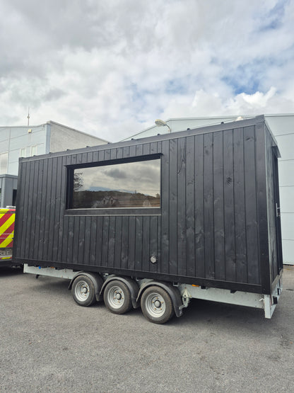 Exterior side view of the Atlantic commercial mobile sauna with panoramic window and tri-axle trailer chassis
