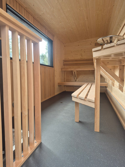 Spacious Atlantic commercial mobile sauna interior with two-tier seating, panoramic window and Altro floor