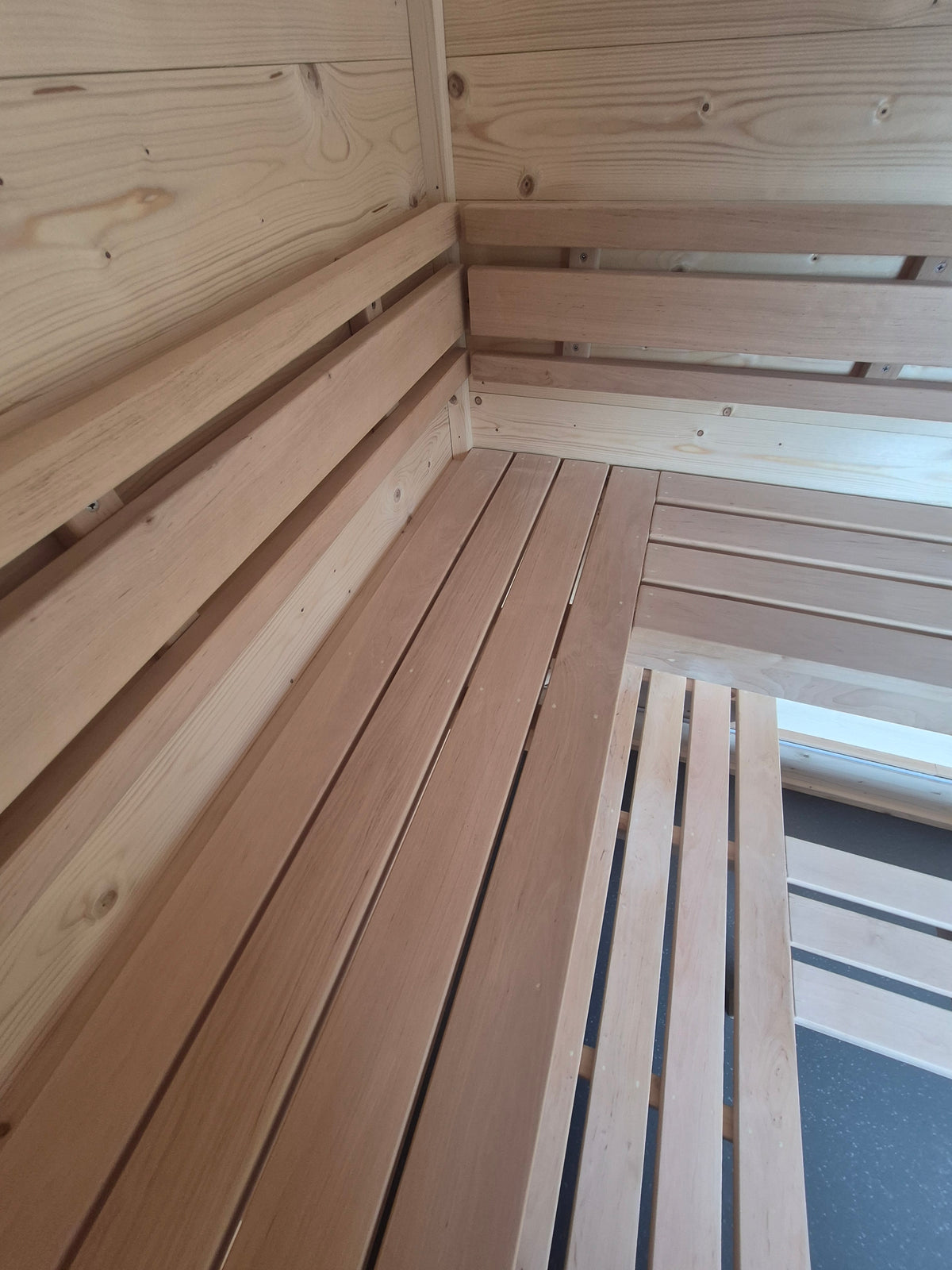 Close-up of handcrafted timber sauna benches and backrests inside the Atlantic mobile sauna