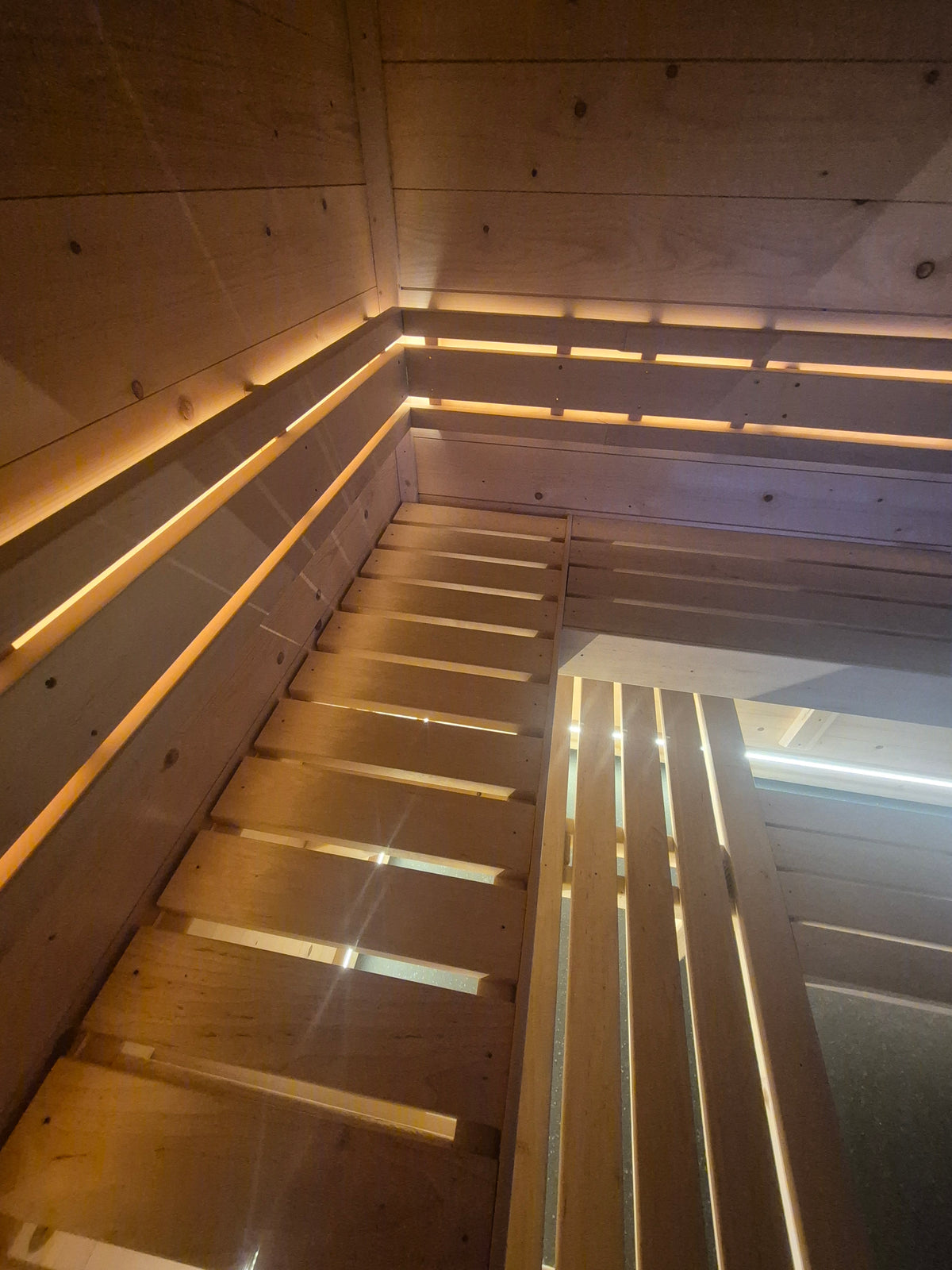 Warm LED lighting integrated into the Atlantic mobile sauna’s timber benches and backrests